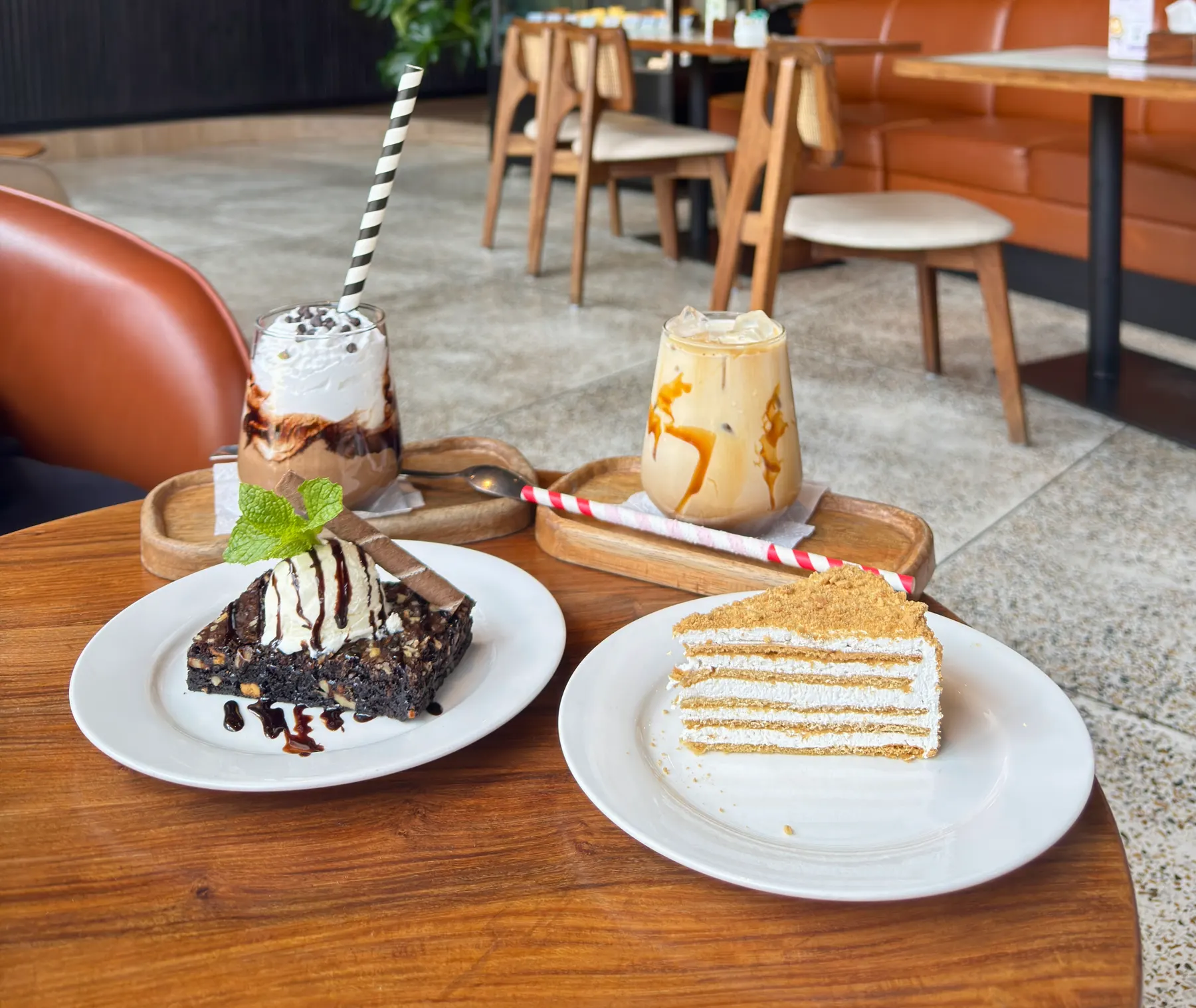 Slice of layered honey cake and a brownie with ice cream on white plates