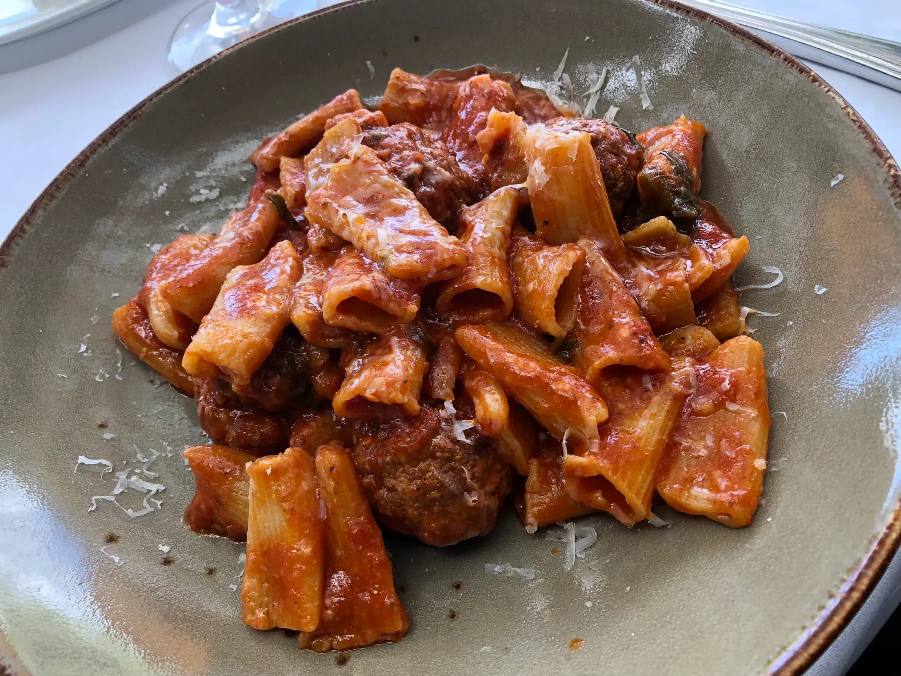 Rigatoni with meatballs in tomato sauce on a stoneware plate