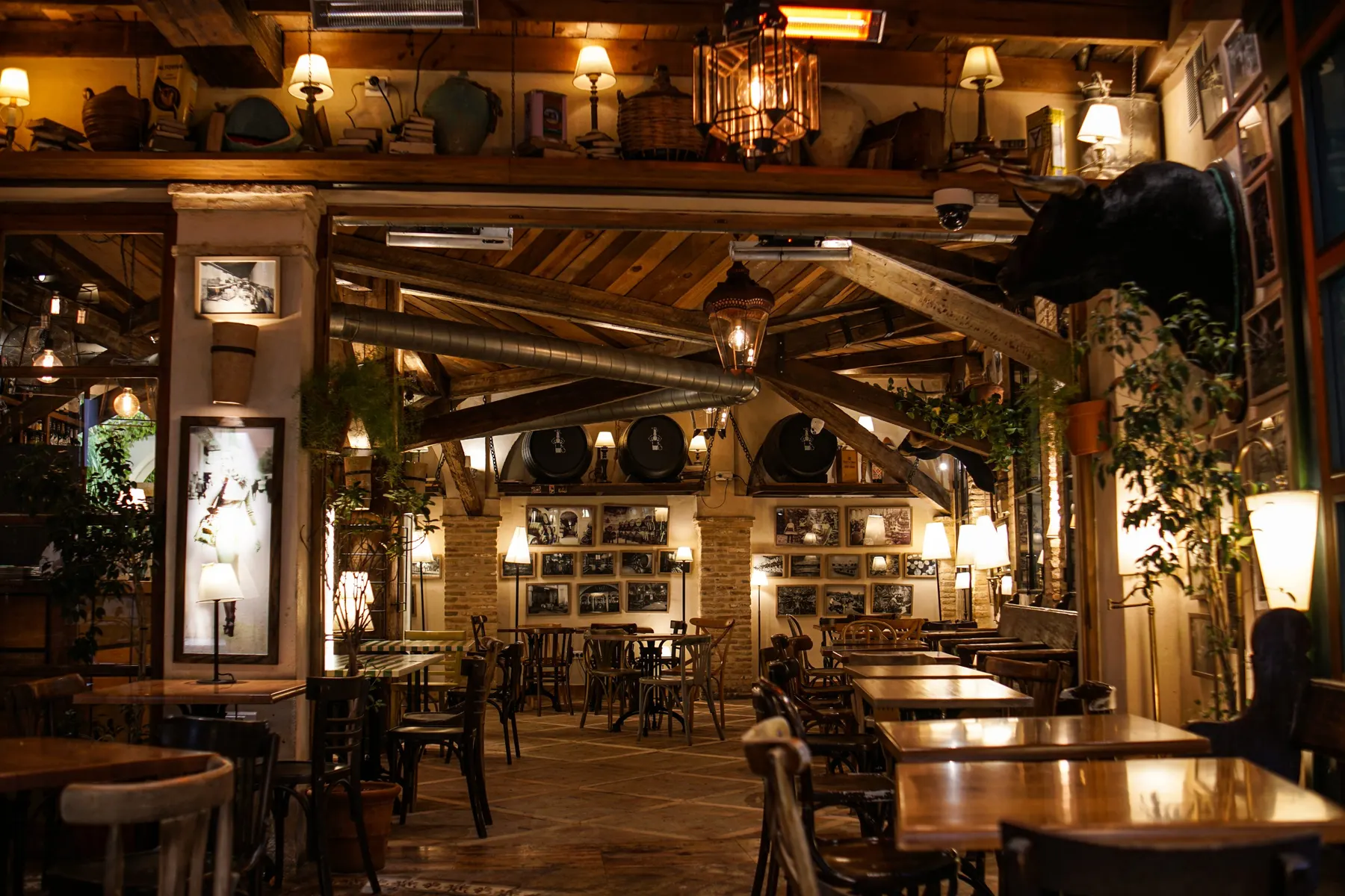 Warm private dining room with wooden beams, hanging lamps and wine barrels on a shelf